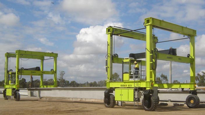 Isoloader Straddle Carriers and Rubber Tyred Gantries (RTGs) work in tandem to handle 60m long precast concrete bridge segments.